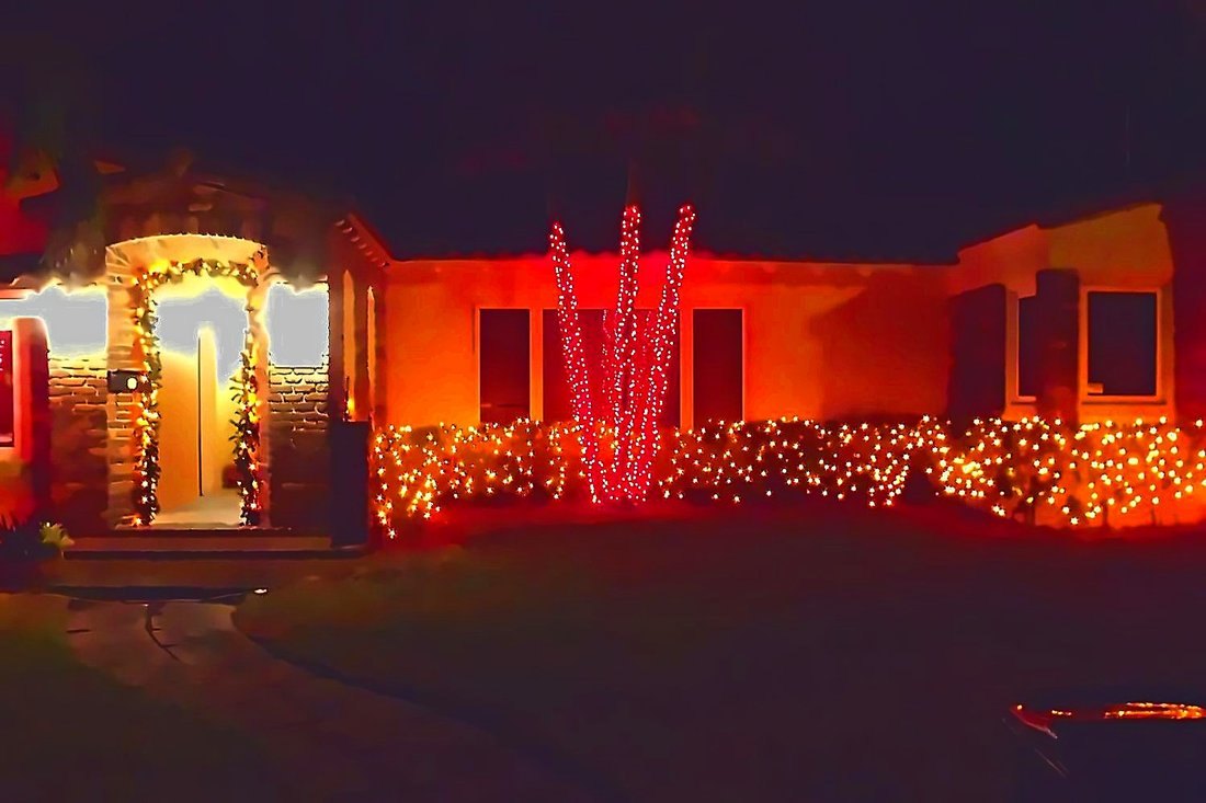 Home entry and hedges lit with warm and red lights at night, Old Northeast St. Petersburg holiday lighting