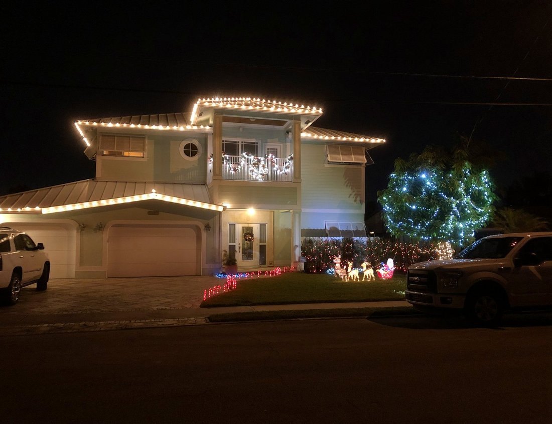 Two-story home with lit roofline and balcony at night, Pasadena and Gulfport holiday lighting