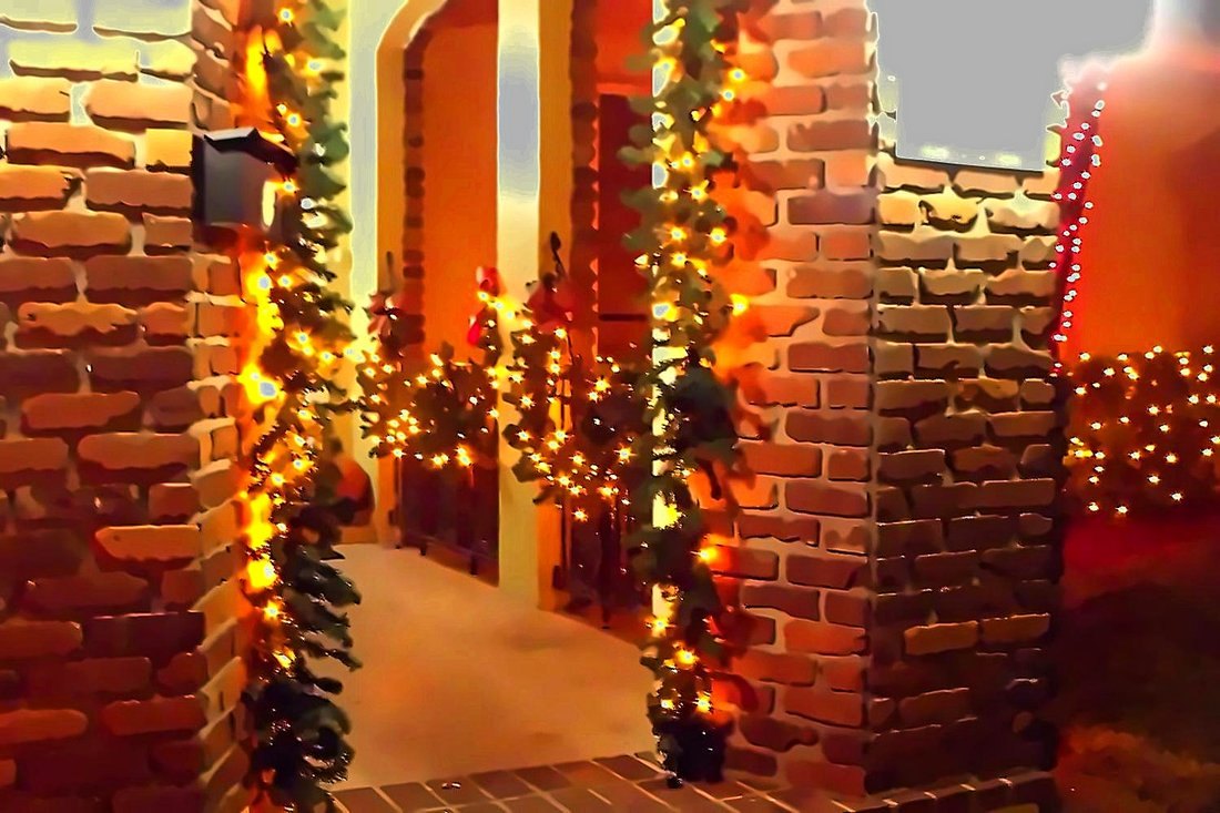 Entryway garland lit warm around a doorway at night, Safety Harbor holiday lighting